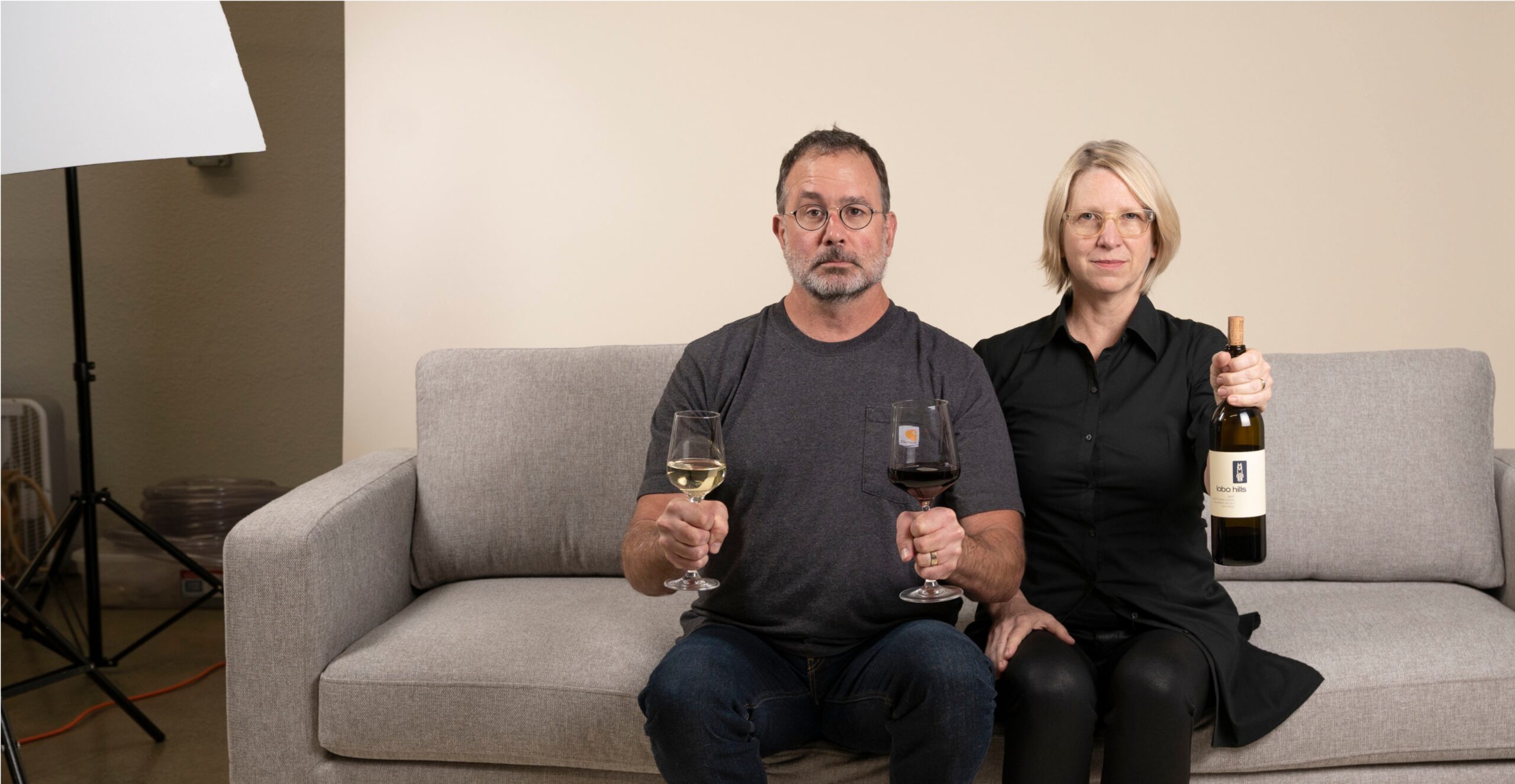 Couple enjoying wine tasting at Lobo Hills Wine Co., holding glasses of white and red wine in a cozy indoor setting.